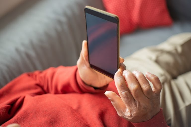 A senior adult comfortably using a smartphone indoors, capturing a moment of modern connectivity.